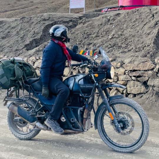 Rider on Royal Enfield Himalayan motorcycle on a mountain road.