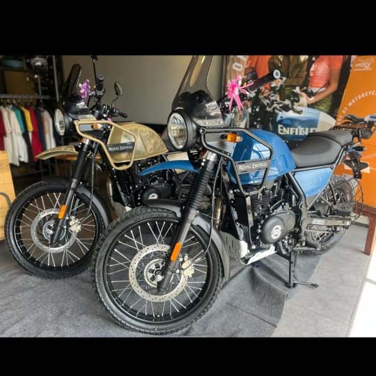 Two Royal Enfield Himalayan motorcycles, one blue and one tan, parked side-by-side.