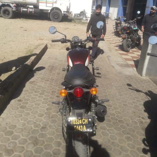 Rear view of a maroon Royal Enfield motorcycle parked, license plate visible: T0324 CH 5443 A